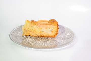 Fresh and tasty charlotte with pear on a gray plate on a white background