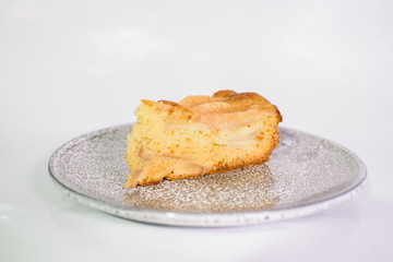 Fresh and tasty charlotte with pear on a gray plate on a white background