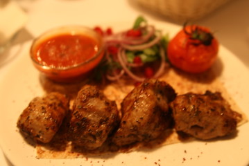 pork shish kebab with salad, sauce and tomatoes on the grill
