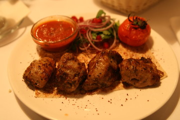 pork shish kebab with salad, sauce and tomatoes on the grill