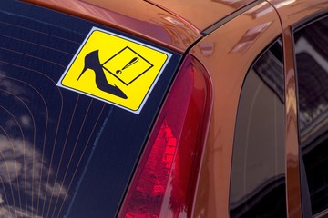 By car sign with a female shoe, which means a woman driving.