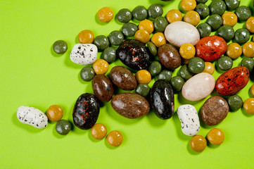 Pebble-dragee with apricots, chocolate, mandarin and marzipan. Tasty, bright, shot on a green background