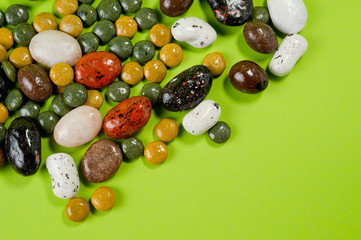 Pebble-dragee with apricots, chocolate, mandarin and marzipan. Tasty, bright, shot on a green background