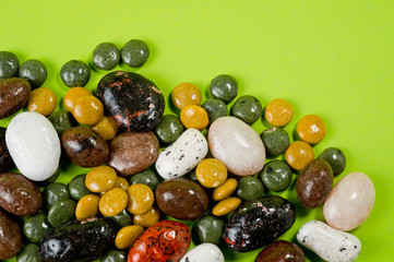 Pebble-dragee with apricots, chocolate, mandarin and marzipan. Tasty, bright, shot on a green background