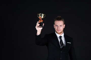 Confident businessman in black suit with Champion Cup