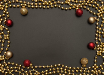Christmas black background with golden beads and red and golden Xmas decorations. Flat lay style. New Year greeting card.