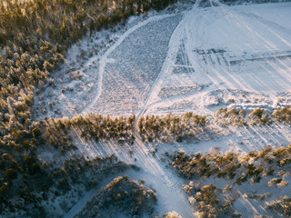 Aerial view on the road and forest at the winter time. Natural winter landscape from air. Landscape in Finland from drone