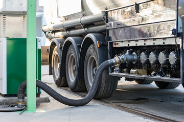 Camion cisterna de mercancias peligrosas suministrando combustible a una estacion de servicio