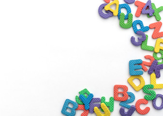 Multi-colored soft English letters and numbers on white background with copy space. Kid's set for teaching reading and counting. Flat lay style.