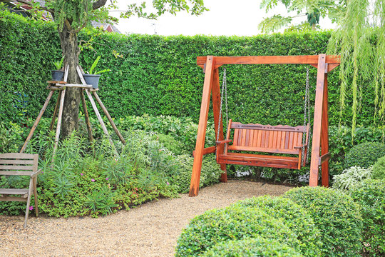 Wooden swing chair in natural green garden. Beautiful garden furniture.