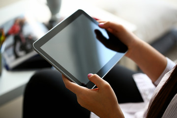 female hand holds tablet in home setting while