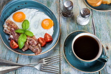 Fried eggs,  bacon, tomato, toast and a cup of coffee