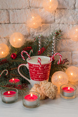 A cup of milk with Christmas candies and coconut cookies on the background of Christmas decorations.
