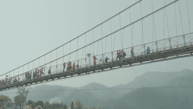 Looking From Below Crowds Of People Crossing A Suspension Bridge In India