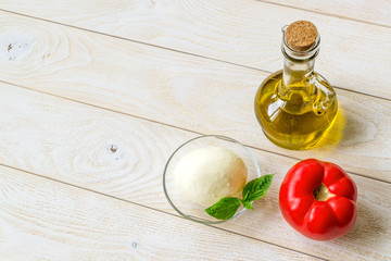 Italian mozzarella cheese, red tomato and olive oil in glass jar on a white rustic wooden table. Healhy eating and vegetarian food. Copy space.