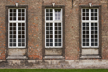 Fototapeta na wymiar Three grunge windows on an old building with red bricks