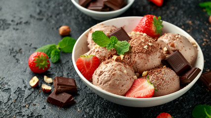 Chocolate Ice Cream with dark chocolate bars, strawberry and hazelnuts in a white bowl