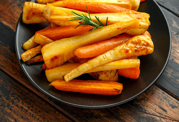 Roasted Parsnips and Carrots with herbs on rustic wooden table