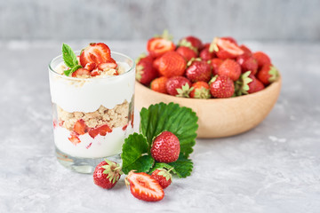 Strawberry granola or smoothie in glass and fresh berries in a wooden bowl. Healthy breakfast