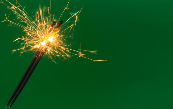 Burning firework sparklers on green background with copy space