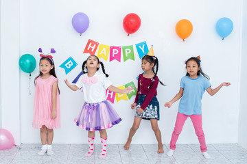 Adorable Asian schoolkids group with beautiful dresses enjoy the birthday party at home with many gift boxes , juices, and bakery