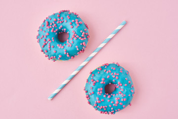 Two blue donuts separated with a drinking straw on pink background. Creative food concept