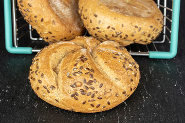 Group of three whole sesame kaiser roll in shopping basket on grey stone