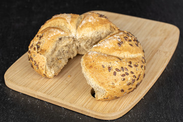 Group of two halves of sesame kaiser roll on bamboo cutting board on grey stone
