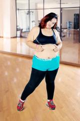 Fototapeta na wymiar Fat Asian woman pinching her belly in the gym