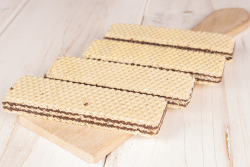 Group of four whole sweet chocolate biscuit wafer on wooden cutting board on white wood