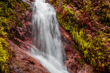 The blurry nature background of waterfalls that flow from a high place and a variety of beautiful water droplets, bokeh, abundance of forests.