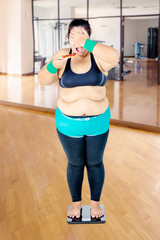 Fototapeta na wymiar Fat woman facing health irony in the gym