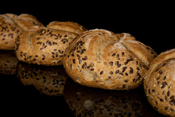 Group of four whole sesame kaiser roll isolated on black glass