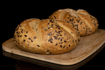 Group of two whole sesame kaiser roll on bamboo cutting board isolated on black glass