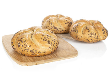 Group of three whole sesame kaiser roll on bamboo cutting board on wooden cutting board isolated on white background