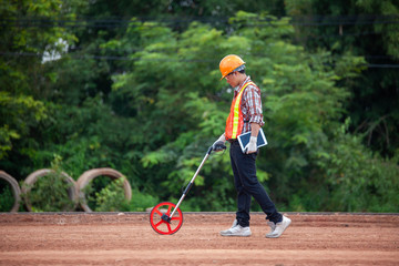 A worker is walking with the measuring wheel, measure the road