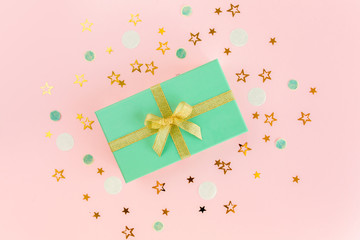 Gift or present box and stars confetti on a pink background. Colorful celebration, birthday, mother day background. Christmas or New Year pattern. Flat lay, top view  
