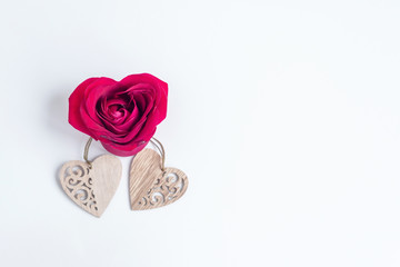 Valentine's day flat lay with a heart-shaped rose and wooden hearts on white background. Minimal, creative concept, copy space