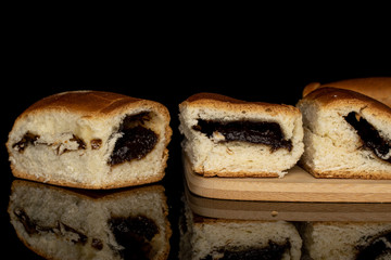 Group of four whole sweet czech bun on bamboo cutting board isolated on black glass