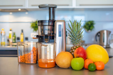 Making fruit juice with juicer machine in home kitchen, healthy eating lifestyle concept