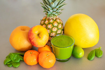 Different tropical fruits and green smoothie on grey background, healthy eating lifestyle concept