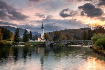 Fototapeta na wymiar Lake Bohinj Church during sunrise in fall season Slovenia Triglav National Park