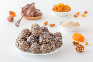 Natural healthy raw energy bites, chocolate paste and mix of dried fruits with nuts on a white table. Close-up