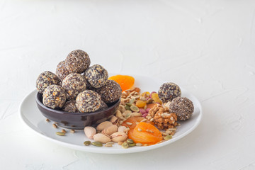Natural healthy raw energy bites, chocolate paste and mix of dried fruits with nuts on a white table. Copy space