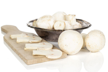 Group of lot of whole four slices of fresh white champignon in glazed bowl on wooden cutting board isolated on white background
