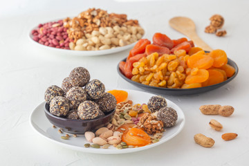 Natural healthy raw energy bites, chocolate paste and mix of dried fruits with nuts on a white table