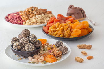 Natural healthy raw energy bites, chocolate paste and mix of dried fruits with nuts on a white table