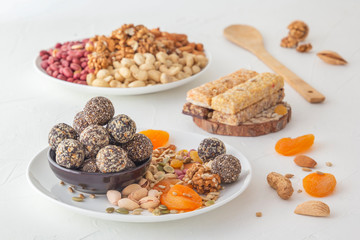 Natural healthy raw energy bites, chocolate paste and mix of dried fruits with nuts on a white table