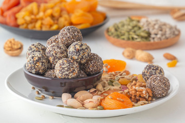 Natural healthy raw energy bites, chocolate paste and mix of dried fruits with nuts on a white table. Close-up