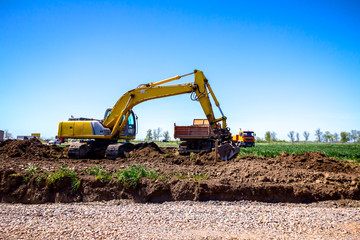 Obraz premium Excavator is loading a truck with ground on building site